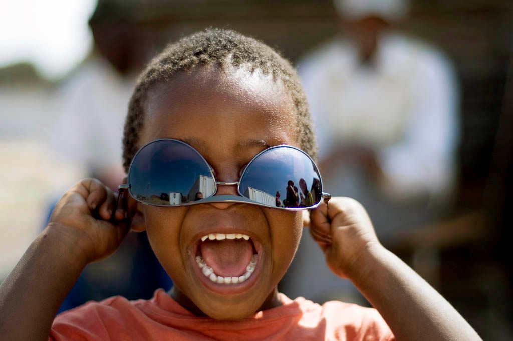 A local child tries on a visitors Sunglasses during a tour of his home area in Soweto, South Africa